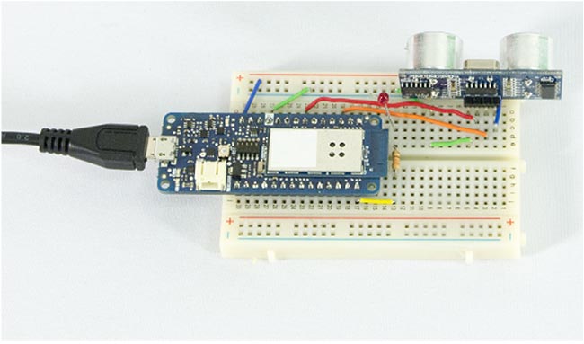 A microprocessor development board connected to an ultrasonic range sensor in a solderless breadboard. The microprocessor is connected to a USB cable for power and programming.