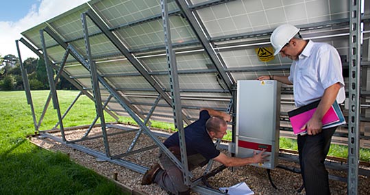 Photograph of solar panel installation being inspected by engineers.